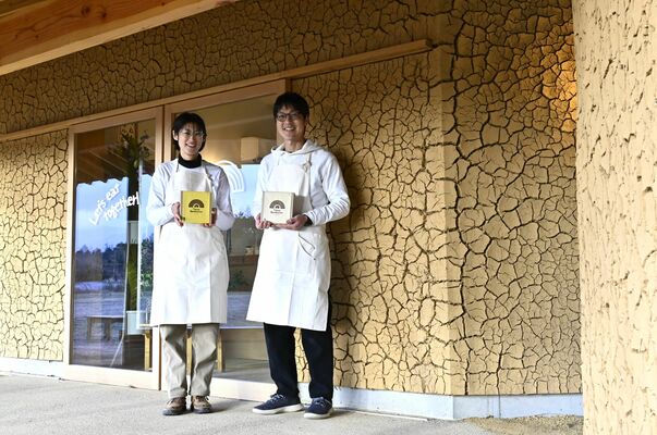 土壁が特徴的な店舗の前に立つ井上さん夫妻