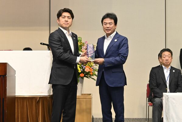 中野洋昌国土交通相（左）からクリスタル盾を受け取る佐藤市長＝５日午後、都内