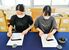 愛媛大大学院生の河野亜美さん（右）が左手で、岡田優佳さんが右手での毛筆を実演。横画を書くとき、右手では筆を引き、左手では筆を押す動きになる＝７月末、松山市文京町の愛媛大