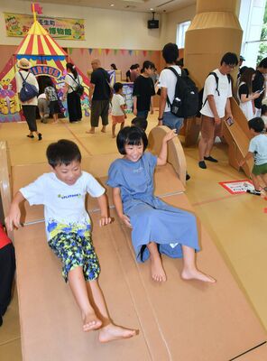 段ボール製の滑り台を笑顔で滑り降りる子どもたち＝15日午後０時15分、壬生町国谷