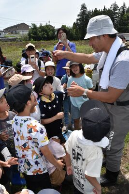 川辺の生き物の解説を聞く子どもたち
