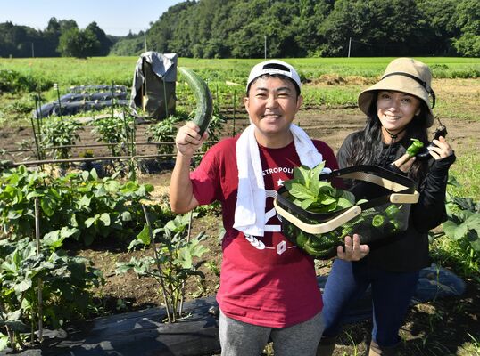 収穫した野菜を手に笑顔を見せる林家三平さん（左）と国分佐智子さん