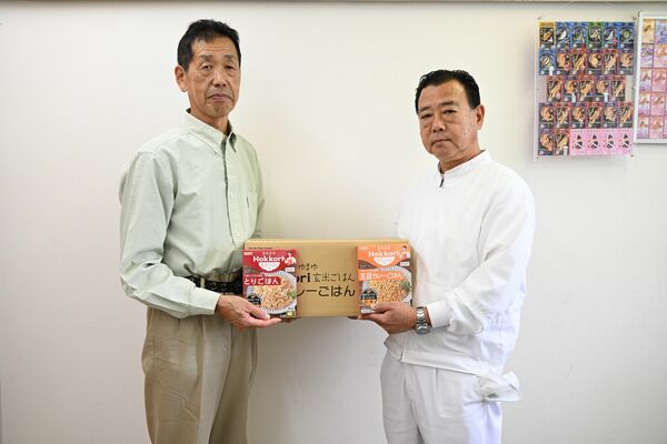 野沢工場長(右)から食品を受け取る君嶋会長=18日午前、宇都宮市