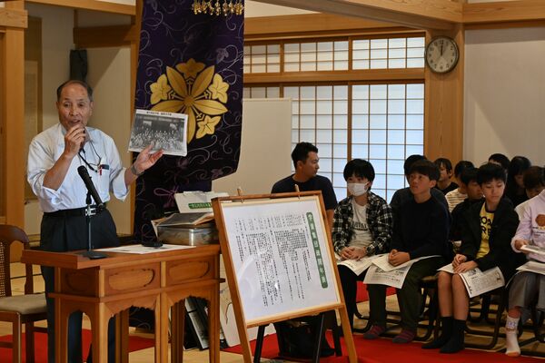疎開児童の集合写真を紹介する小倉さん（左）