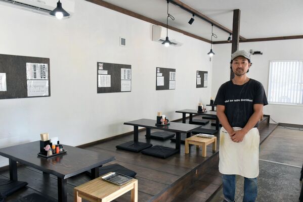 茶色と白でまとめた開放的な店内に立つ床井さん