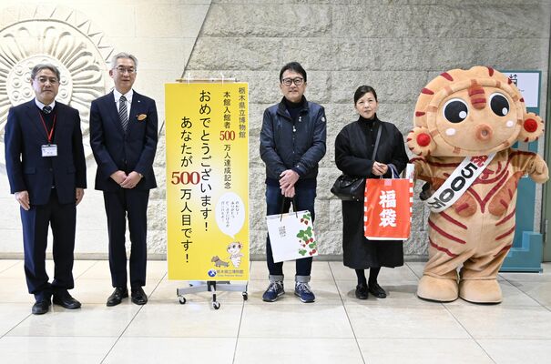 県立博物館の本館入館５００万人目となった篠原夫妻（中央）ら＝14日午後、宇都宮市睦町