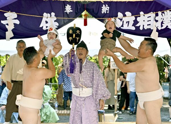力士姿の氏子に抱えられて、元気な泣き声を響かせる子どもたち＝21日午前９時10分、鹿沼市樅山町