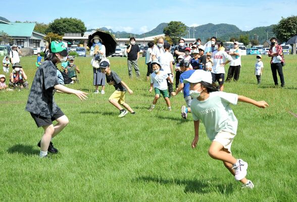 鈴を身に付け、目隠しした鬼から逃げ回る子どもたち
