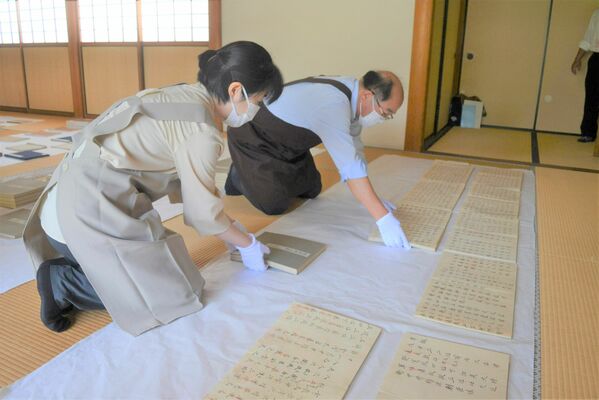 貴重な古書を丁寧に広げて虫干しする職員