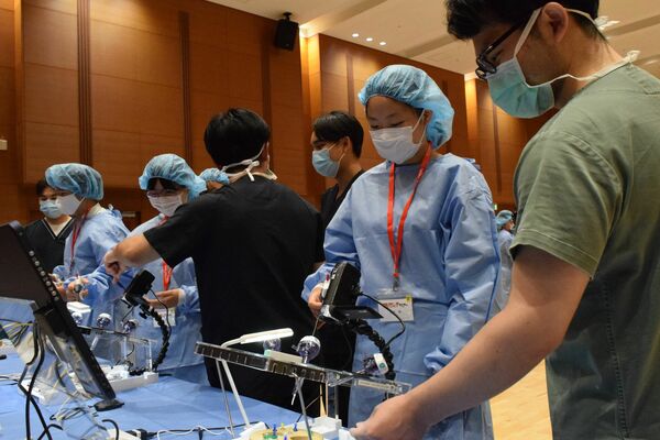 医師の指導を受けながら内視鏡トレーニングを体験する中学生ら＝19日午後、宇都宮市竹林町