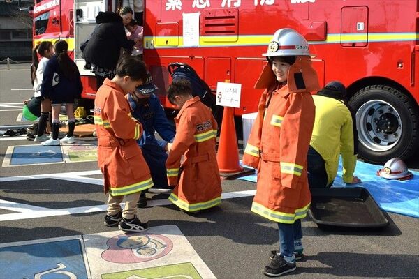防火衣の着用体験を行う子どもたち