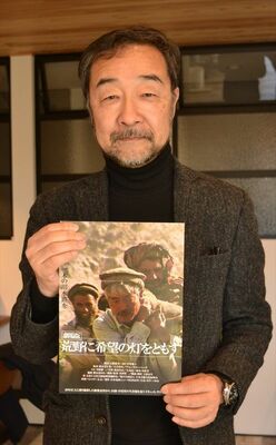 上映会のチラシを手にする谷津監督