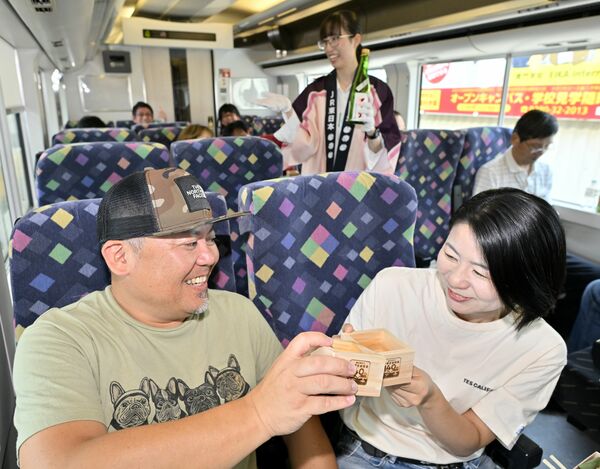 沿線の地酒で乾杯する乗客＝26日午前11時25分、ＪＲ宇都宮線