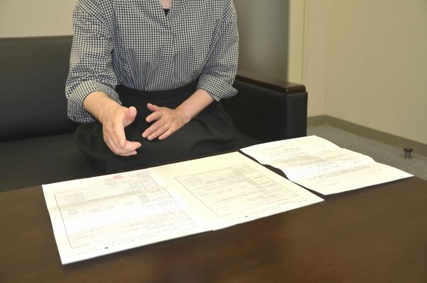 就業条件などを示した書面を基に状況を説明する女性