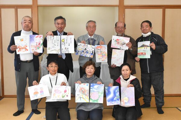 配食する包装紙のデザインを見せる会員たち