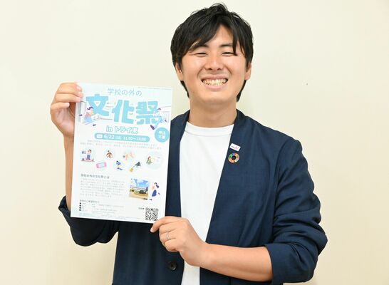 「学校の外の文化祭」のチラシ手にする浜塚センター長