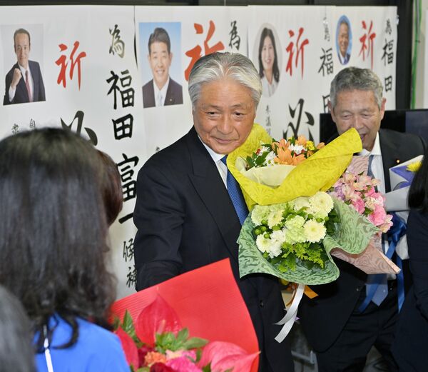 6選を確実にし、花束を受け取る福田富一氏(中央)=17日午後7時5分、宇都宮市戸祭町