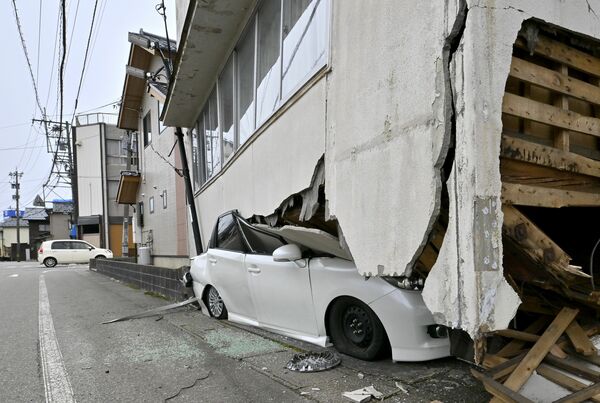 乗用車を巻き込んで崩れた住宅。地震の爪痕は今も多くの場所に残る＝２月29日午後４時５分、石川県穴水