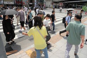署名活動への協力を求め、通行人にチラシを手渡す多恵子さん（手前中央）＝22日午後、東京都内