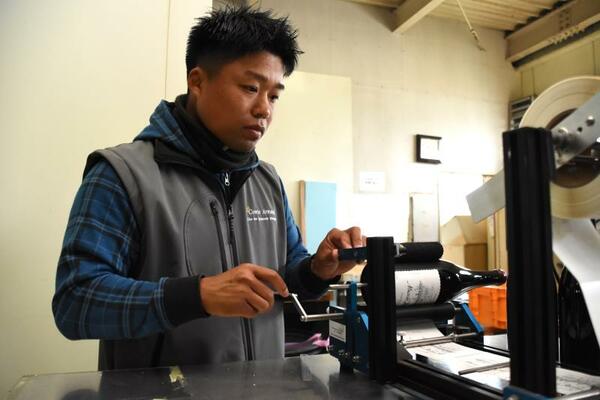 完成した大平産ワインにラベルを貼る岩崎さん
