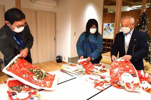 ブックサンタの本をプレゼント用に包装するキャリアコーチの高木さん（右）ら＝19日午後、大田原市若草１丁目