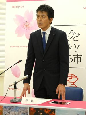会見の冒頭、立って所信表明を行う中村市長
