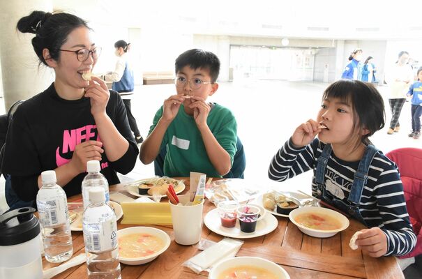 もち麦チップスをほおばる親子連れ