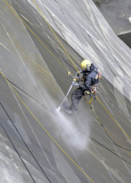 松田川ダムの堤体に高圧洗浄機でアートを描く作業員