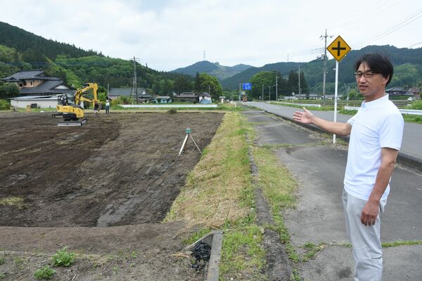 重機を入れて田んぼ復元作業を行う蔵の前の耕作放棄地と案内する渡邉社長＝５月、大田原市