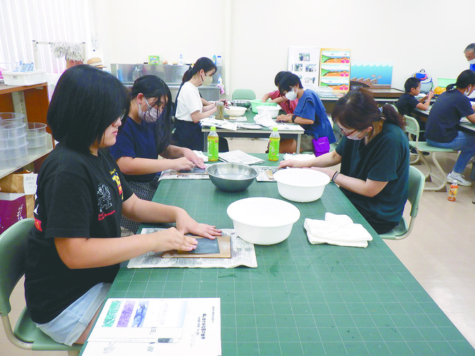 昨年８月に行われた理系女子セミナーの様子。紙やすりで化石を磨く参加者（提供写真）