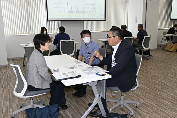 進路担当者（左）に事業概要などを説明する企業関係者ら＝13日午後、宇都宮市