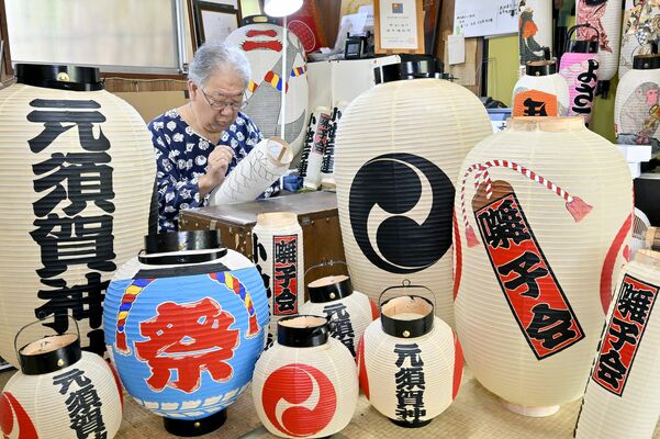 ちょうちんが並ぶ作業場で筆を握る田中さん＝５日午前10時20分、栃木市藤岡町新波