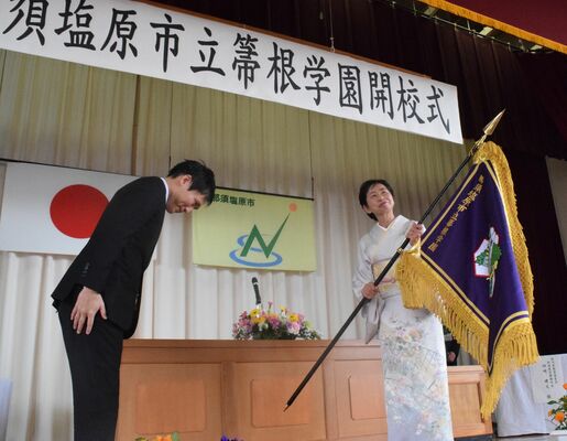 渡辺市長（左）から真新しい校旗を受け取る山本校長
