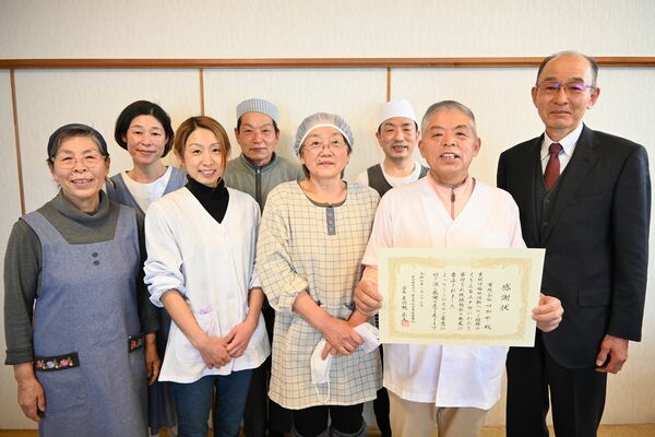 赤羽根会長（右）から感謝状を受けた「つがや」の五百部さん（右から２人目）と従業員