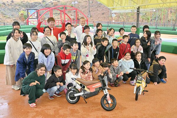 Ｕ字工事と集合写真を撮る須藤小の児童ら