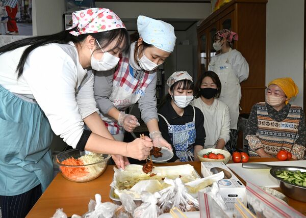各家庭に配る料理を取り分けるスタッフやボランティア＝25日午後２時55分、真岡市内