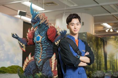　作中で共に戦う怪獣レキネスのフィギュアの前でポーズをとる吉田晴登