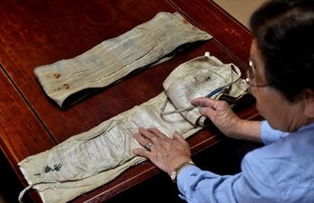 千人針を縫い込んだ長兄の遺品の腹巻きを手にする小池秀子さん。無事帰還の願いを込めたクルミ(来る身)やお守りも縫い込まれていた=2015年6月4日、高根沢町宝積寺