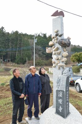 法幢寺近くに立つ道標を見上げる清宮さん（中央）と松山さん（右）、磯さん