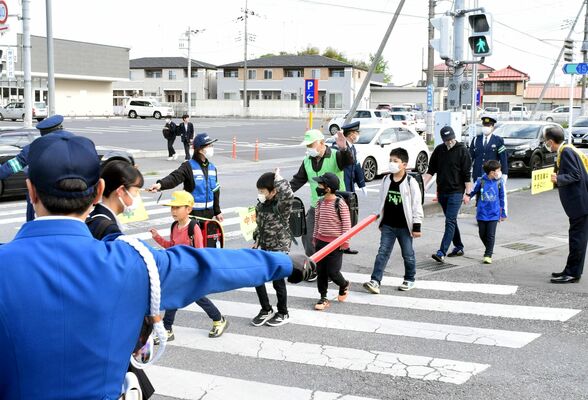 警察官や地域住民らに見守られながら登校する児童たち＝18日午前７時45分、鹿沼市樅山町