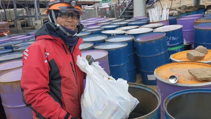 南極で出たごみをドラム缶に入れる金重隊員＝2022年１月、南極・昭和基地の焼却炉棟前