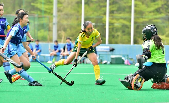 ホッケー女子決勝　第１クオーター、今市のＭＦ鷲頭（中央）がドリブルで持ち込みシュートを放つ＝日光市ホッケー場