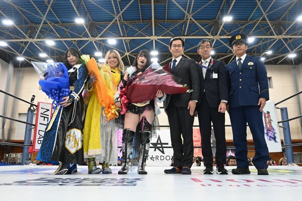 リング上で坂村市長（右から３番目）らから花束を手渡された３姉妹（左の３人）