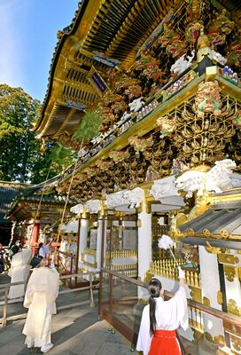 笹竹などで陽明門の汚れをはらい清める神職とみこ＝20日午前10時10分、日光市山内