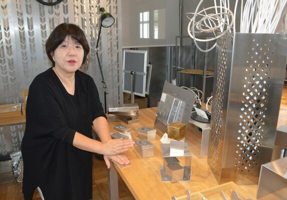 ギャラリーで、精密板金加工技術で作られた作品について説明する谷内社長