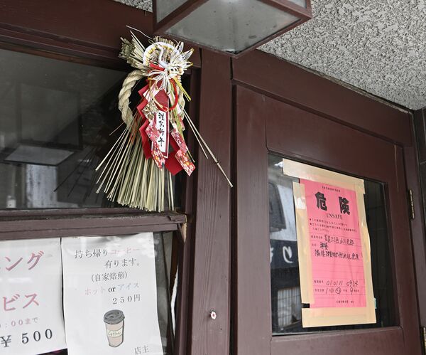 入り口に正月飾りが飾られたままの喫茶店。隣には立ち入りの危険を示す赤い紙が貼られていた＝14日午前９時25分、石川県輪島市