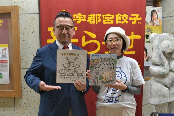 絵本を手にする玉田さん（右）と宇都宮餃子会の鈴木事務局長