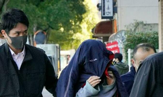 家宅捜索に立ち会うため、捜査員に連れられて自宅に入る吉井辰夫容疑者(中央)=26日午前、福岡市早良区