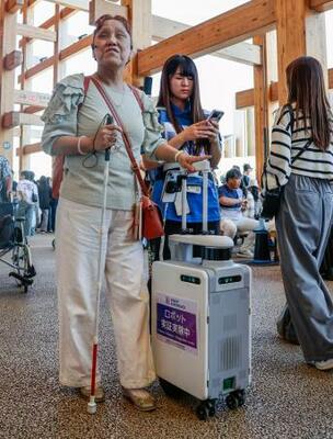 大阪・関西万博会場で「AIスーツケース」の実証実験に参加した久保田真智子さん(左)=10月、大阪市此花区の夢洲