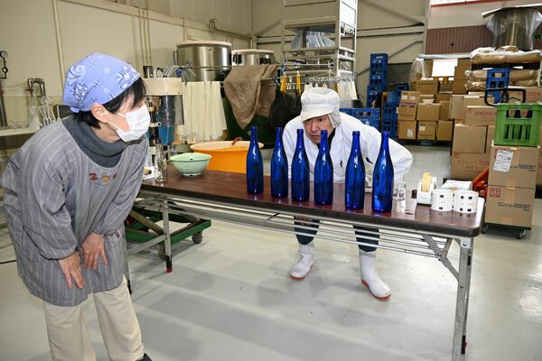 火入れして膨張した酒の水位を確認する寺澤製造部長（右）＝２月１１日、鹿沼市上粕尾